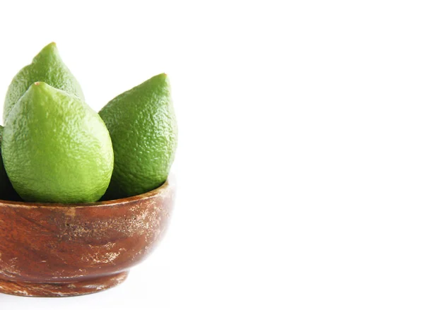 Fruits de citron vert citron vert naturel dans un brun en bois une assiette — Photo