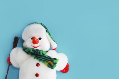 Yeni yıl tatili için mavi bir arka plan üzerinde beyaz kürk ceket ve şapka Noel dekoratif oyuncak kardan adam