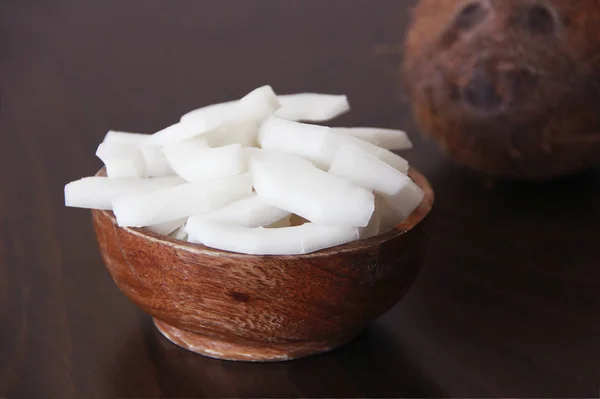 Noix de coco brune et tranches de noix de coco blanche naturelle dans une assiette en bois — Photo