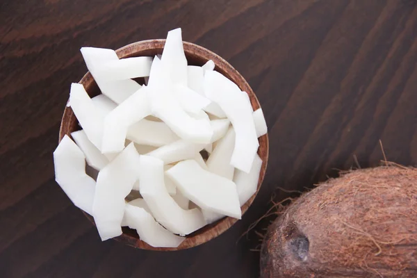 Fruta de coco marrón y rodajas de coco blanco natural en un plato de madera — Foto de Stock