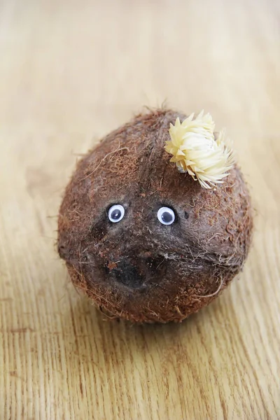 Fruta de coco marrón natural con ojos sobre fondo de madera — Foto de Stock