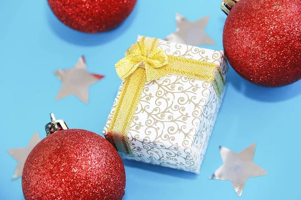 Різдвяні різнокольорові блискучі червоні кульки дерев'яні прикраси та подарункова коробка з жовтим бантом на новорічне свято . — стокове фото