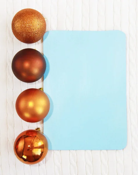 blue postcard on the background of white texture of woolen fabric with pigtail pattern and orange Christmas toys a balls