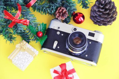 Yeşil ağaç dalı ve sarı arka planda Noel dekoru olan klasik fotoğraf makinesi.