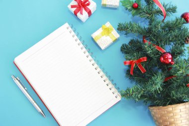 Notlar için not defteri ve yeni yıl dekorlu yeşil bir Noel ağacı.