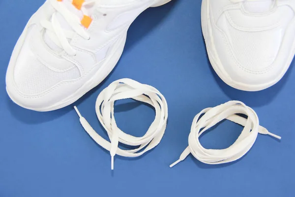 Zapatillas deportivas y cordones blancos sobre fondo azul — Foto de Stock