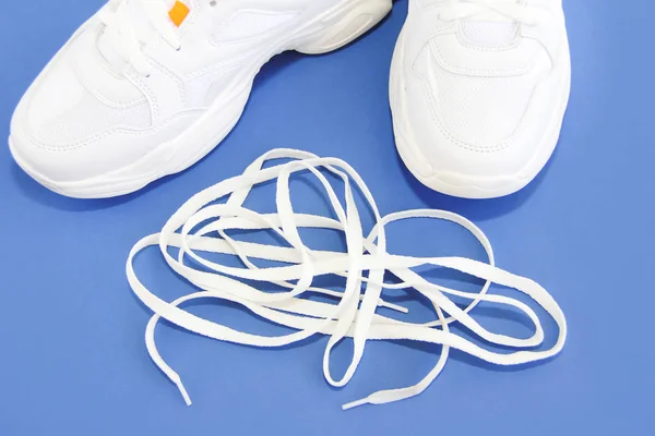 Witte schoenveters en sportschoenen sneakers op een blauwe achtergrond — Stockfoto