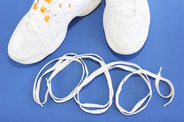 Zapatillas deportivas y cordones blancos sobre fondo azul — Foto de Stock