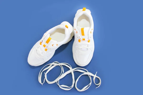 Białe sznurowadła i buty sportowe trampki na niebieskim tle — Zdjęcie stockowe