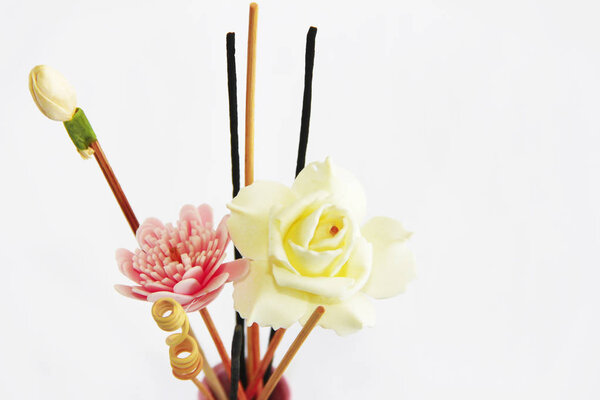 aromatherapy sticks and decorative artificial flowers in pink ceramic vase