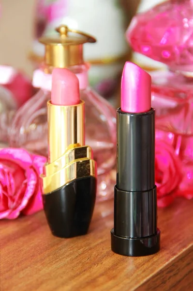 pink decorative lipstick on the background of perfume a bottles