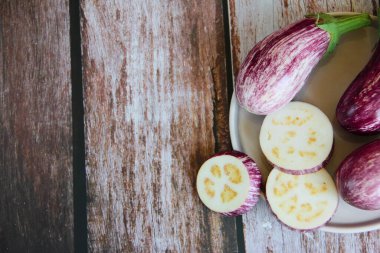 Çizgili mor patlıcan ve patlıcan dilimleri dekoratif bir tabakta.