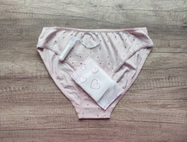 Ahşap arka planda kadın iç çamaşırı, hijyenik pedler ve tamponlar.