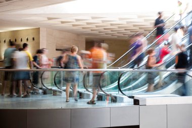 Yürüyen merdivendeki insanlar, yoğun saatler, hareket bulanıklığı