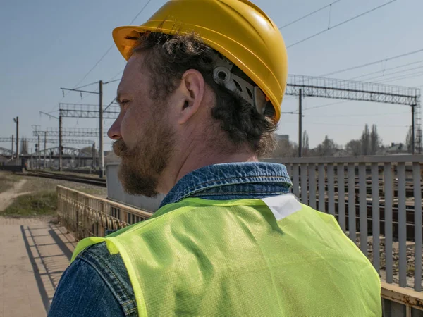 portrait of a man with a beard and mustache in a helmet against the background of railway track.railway worker
