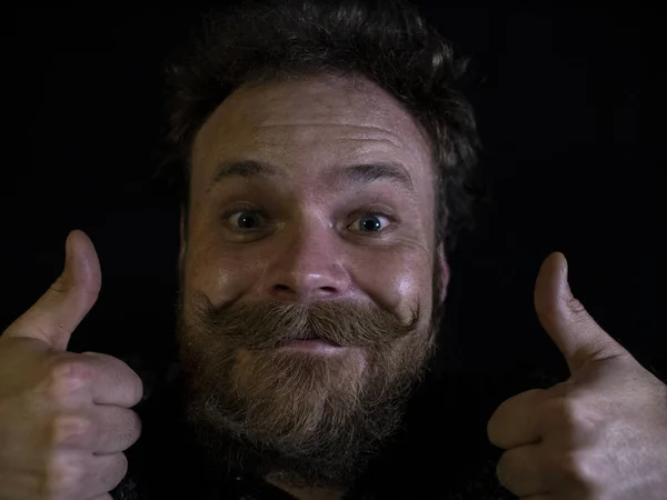 funny face of a man with a beard and mustache close up and showing thumbs up