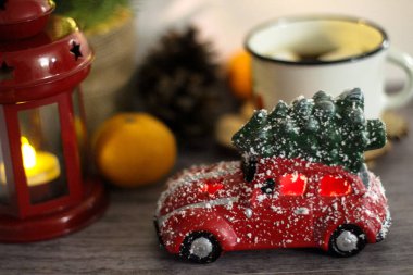 Kırmızı oyuncak araba ile Noel ağacı çatıda. Beyaz arka plan bulanık Kupası, kırmızı fener, mandalina. Tatil kavramı