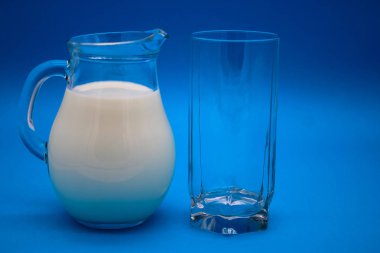 Süt ve mavi bir arka plan üzerinde boş cam sürahi