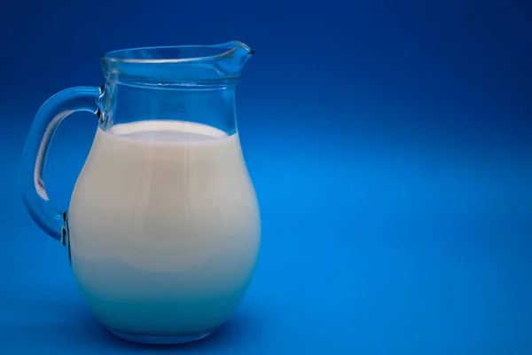 青色の背景にミルクの水差し — ストック写真