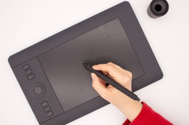 Bir kadın eli kırmızı bir kol bir grafik tablet kalem çizer. Beyaz bir arka planda izole görüntüdür.