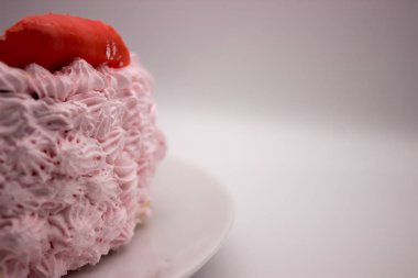 Beyaz-gri arka plan üzerinde bir plaka üzerinde pembe bir kek parçası. Resim kopyalama alanı alanı ile.