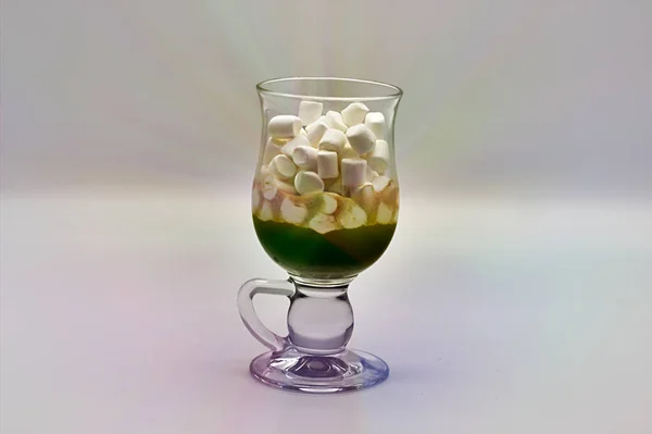 Coffee and many small marshmallows in a transparent glass cup on