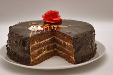 Beyaz arka planda çikolatalı kek. Yukarıdan görüntü. Pasta krem kırmızı bir çiçek ve G-Clef ile stilize müzikal tarzı ile dekore edilmiştir