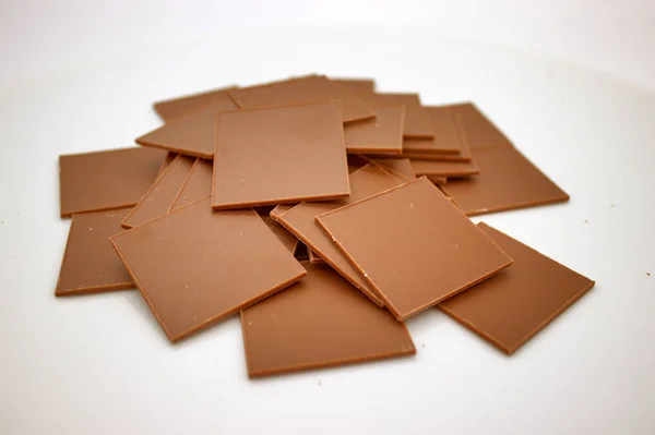 Carreaux carrés minces de chocolat sont placés sur un fond blanc — Photo