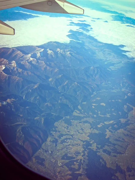 Blick aus dem Flugzeug auf Berge und Wolken. Flugzeugreise phot — Stockfoto