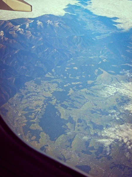 Blick aus dem Flugzeug auf Berge und Wolken. Flugzeugreise phot — Stockfoto