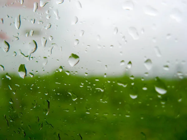 車の窓に雨が降る。窓の後ろに広がる青い風景 — ストック写真