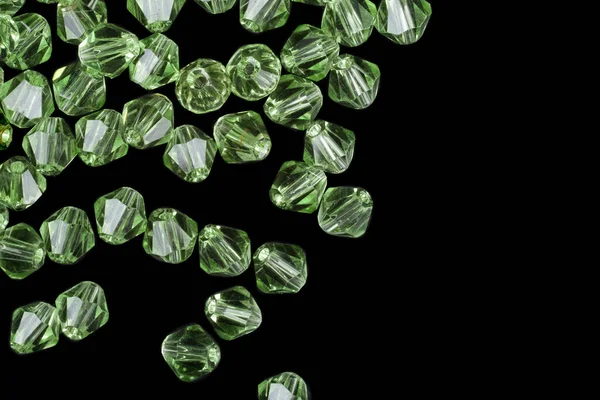 Green gemstones are scattered on a black background
