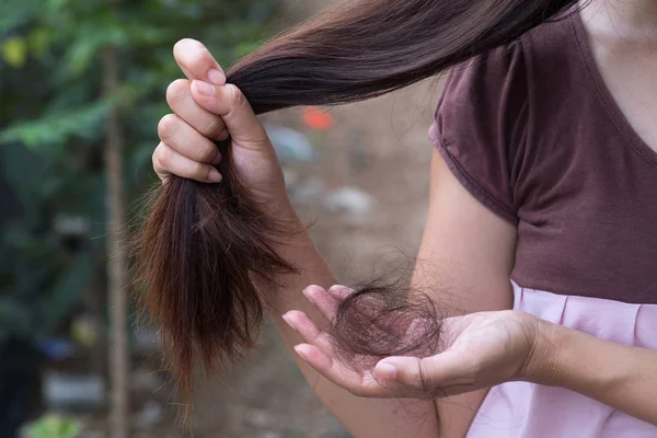 Weak health. Depressed cheerless woman looking at the tuft of hair while having health problems.