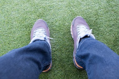 Dışarı bir yeşil suni çim futbol sahası üzerinde yırtık kot pantolon erkek spor ayakkabı.