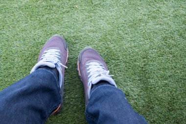 Dışarı bir yeşil suni çim futbol sahası üzerinde yırtık kot pantolon erkek spor ayakkabı.