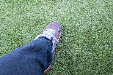 Dışarı bir yeşil suni çim futbol sahası üzerinde yırtık kot pantolon erkek spor ayakkabı.