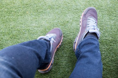 Dışarı bir yeşil suni çim futbol sahası üzerinde yırtık kot pantolon erkek spor ayakkabı.