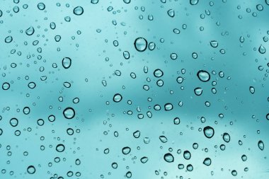 Mavi arka plan, cam üzerine doğal su damlası.