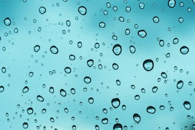 Mavi arka plan, cam üzerine doğal su damlası.