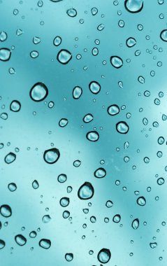 Mavi arka plan, cam üzerine doğal su damlası.