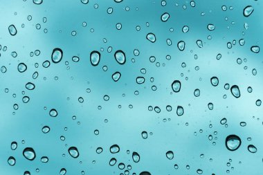 Mavi arka plan, cam üzerine doğal su damlası.