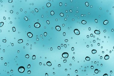 Mavi arka plan, cam üzerine doğal su damlası.