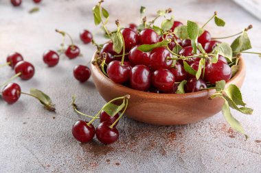 Taş arka plan üzerinde yaprakları ile taze tatlı kiraz kase, üst görünümü