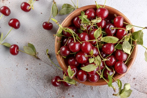 Taş arka plan üzerinde yaprakları ile taze tatlı kiraz kase, üst görünümü