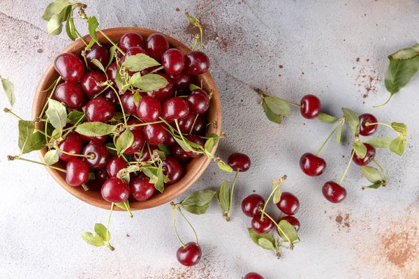 Taş arka plan üzerinde yaprakları ile taze tatlı kiraz kase, üst görünümü