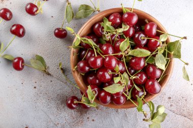 Taş arka plan üzerinde yaprakları ile taze tatlı kiraz kase, üst görünümü