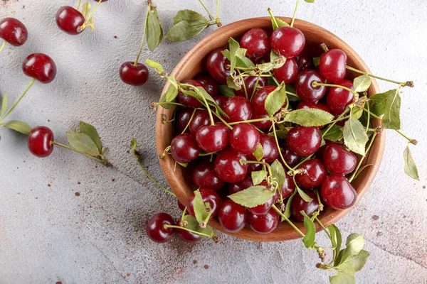Taş arka plan üzerinde yaprakları ile taze tatlı kiraz kase, üst görünümü