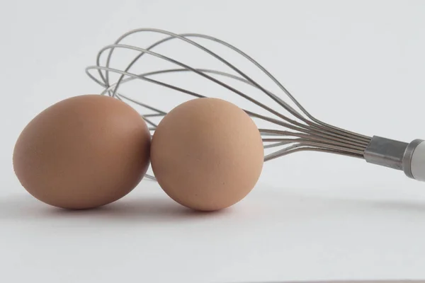 iki taze yumurta beyaz arka plan üzerinde izole çırpma teli ile.