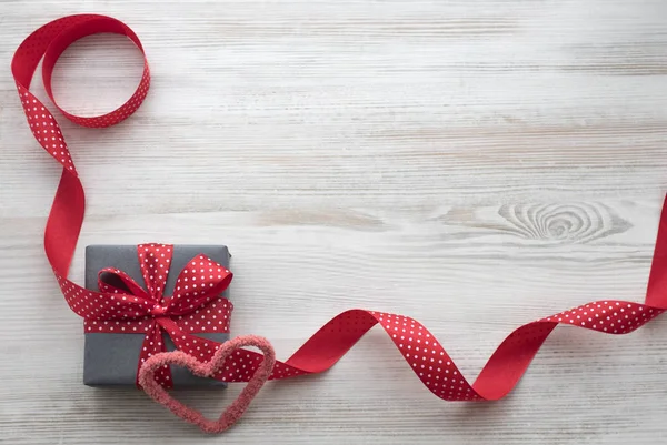 Çizgili backgraund üzerinde kırmızı kurdele ile gri hediye kutusu