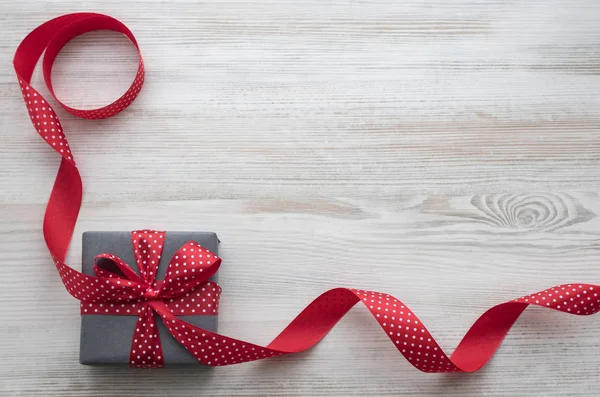 Çizgili backgraund üzerinde kırmızı kurdele ile gri hediye kutusu